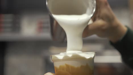 barista vertiendo leche espumosa sobre freddo cappuccino en cámara lenta