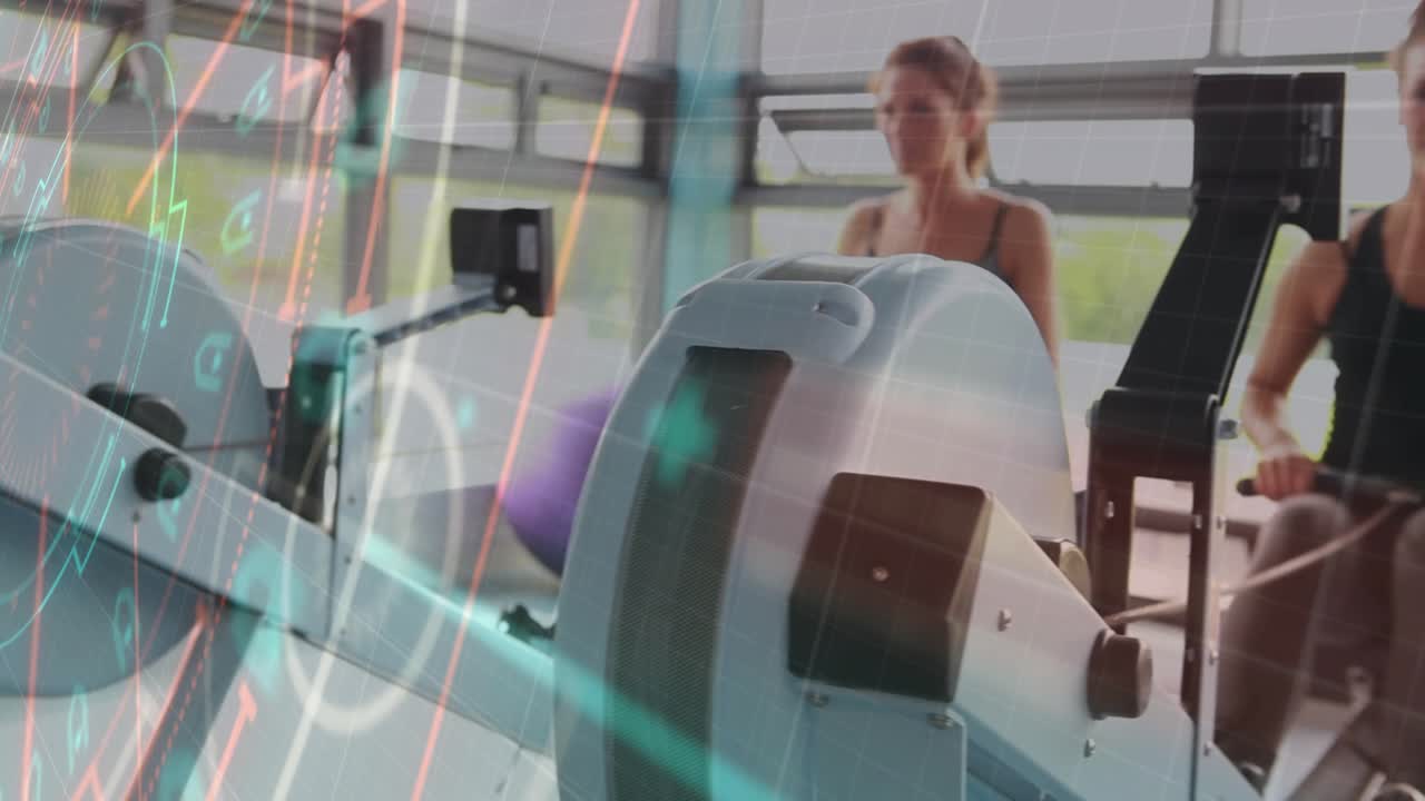 Women rowing in fitness training, neon overlays appearing as camera shifting, flywheels dominating