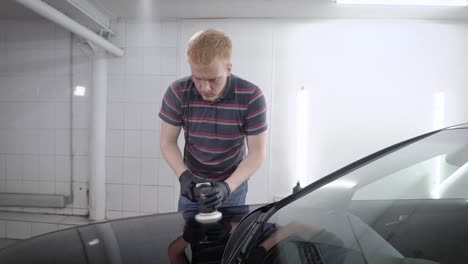 man sedulously polishing bumper of car