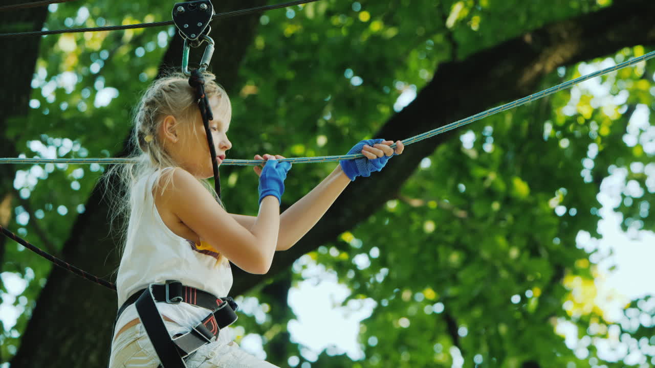 un niño valiente camina por la cuerda floja entre árboles altos infancia activa y diversión