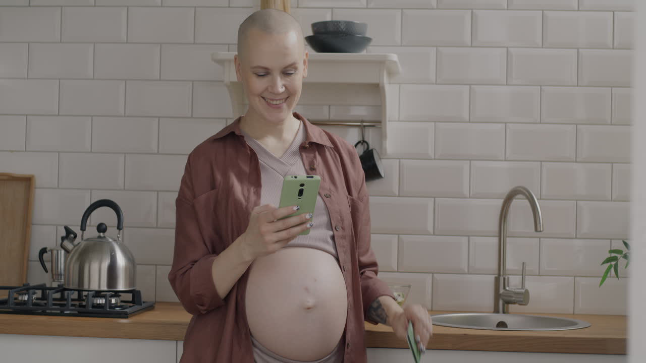 Pregnant Woman Using Smartphone and Credit Card in Kitchen