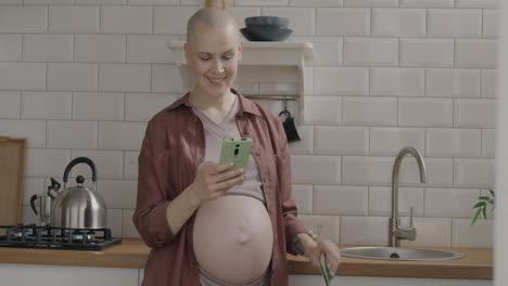 pregnant woman using smartphone and credit card in kitchen