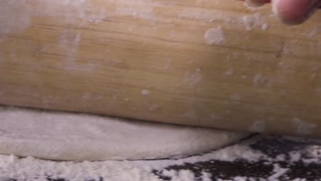 stretching pizza dough close up shot from rolling pin moving forward