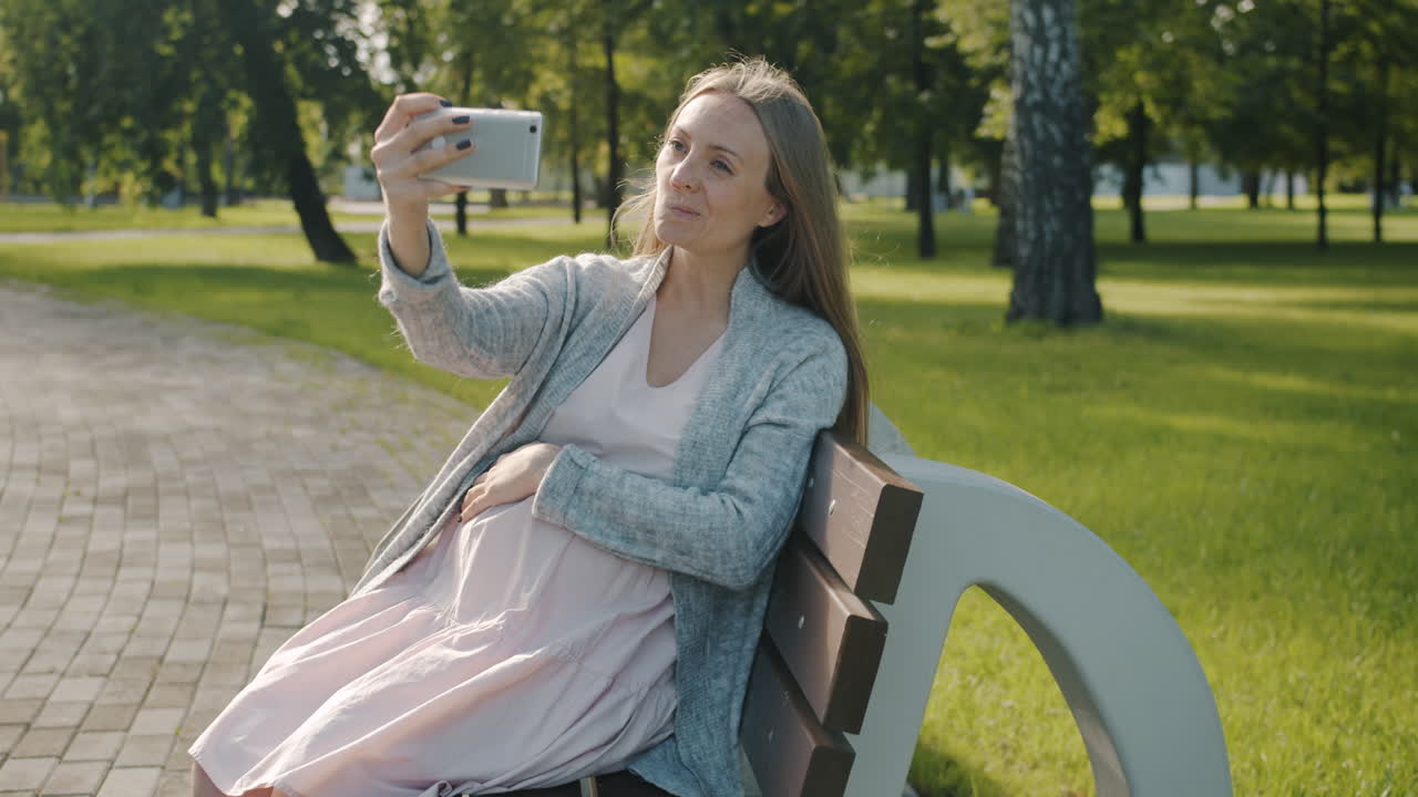 Pregnant Woman Taking a Selfie in a Park