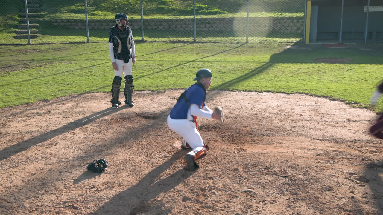 Playing baseball, catcher in gear catching ball with umpire watching