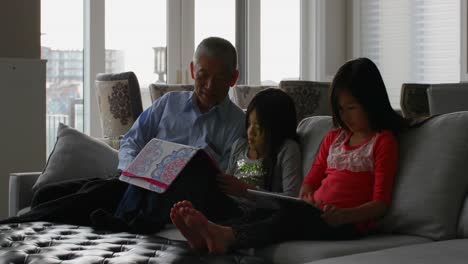 Front-view-of-old-senior-asian-grandfather-and-cute-granddaughters-using-digital-tablet-at-home-4k