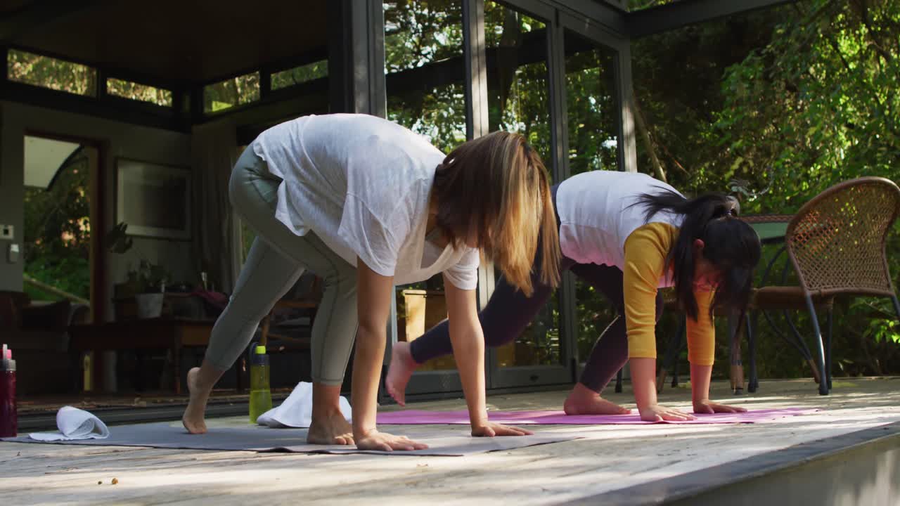 madre y hija asiáticas practicando yoga al aire libre en el jardín