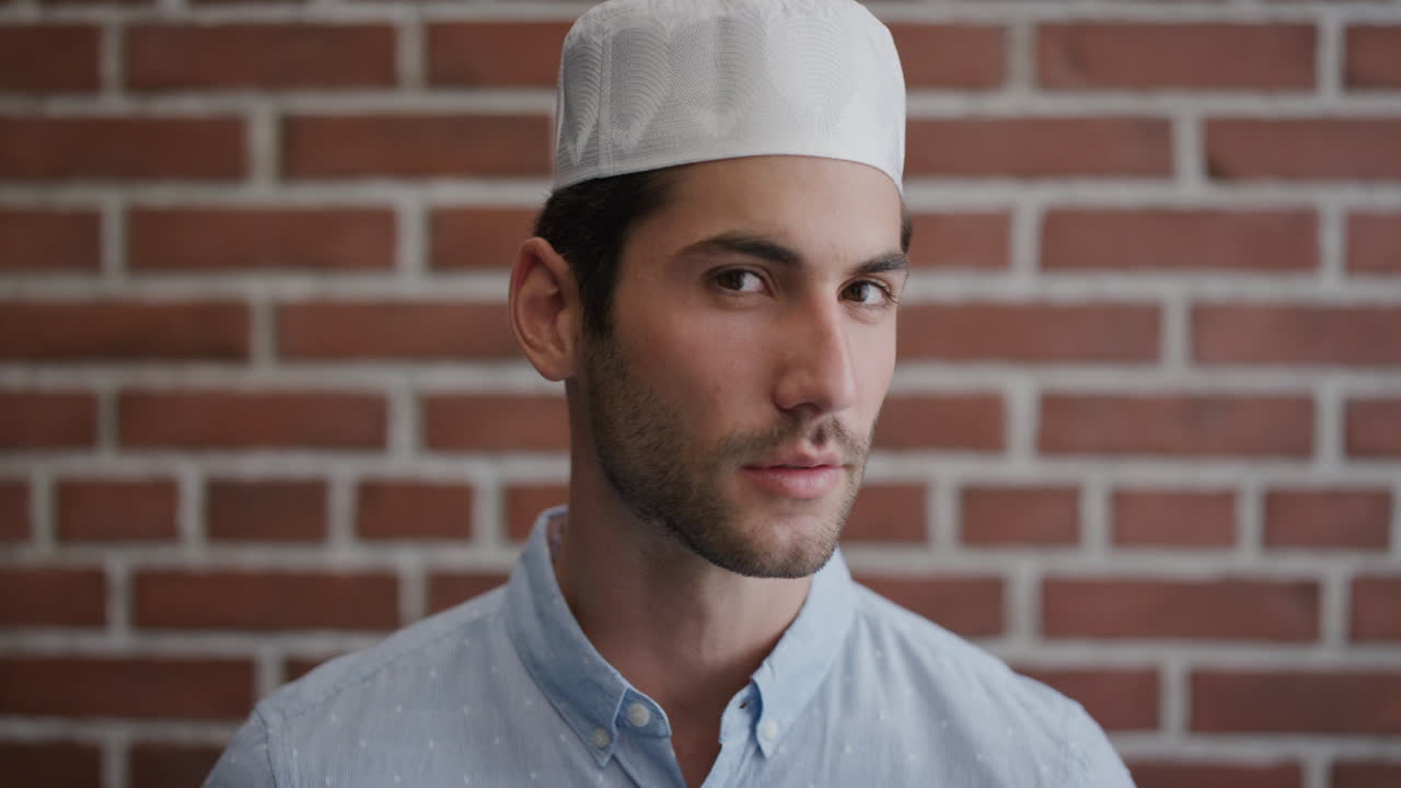 초상화 매력적인 젊은 무슬림 남자가 돌아서 생각나는 모습을 하고 머리를 돌리고 자신감 있는 독립적인 사업가가 쿠피 모자를 입고 슬로우 모션