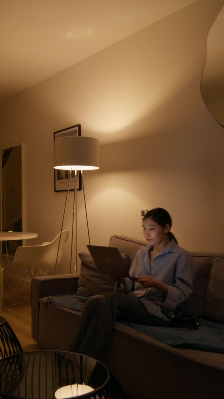 mujer trabajando en una computadora portátil en la sala de estar por la noche