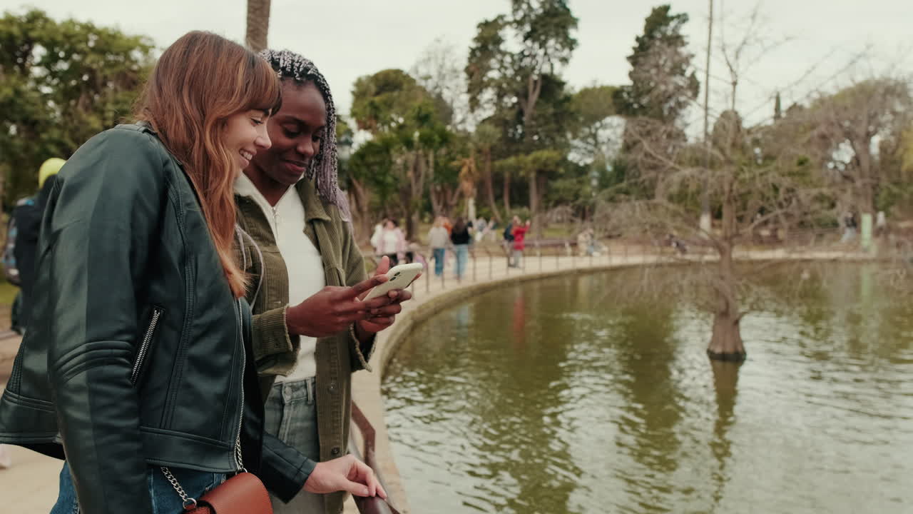Giovani donne felici che condividono un momento accanto a un laghetto in un parco