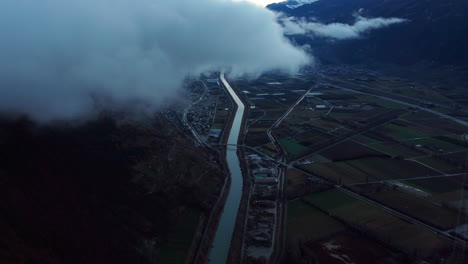 Vista-Aérea-Del-Río-Rhone-Fluyendo-A-Través-De-Martigny-Con-Nubes-Bajas