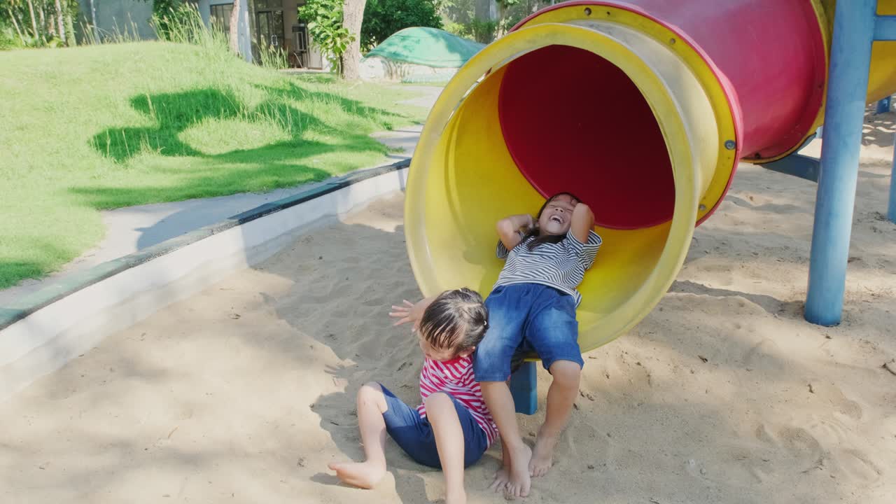 hermanas pequeñas activas jugando en diapositivas coloridas en el patio de recreo al aire libre. niñas felices sonriendo y riendo en el parque infantil. jugar es aprender en la infancia.
