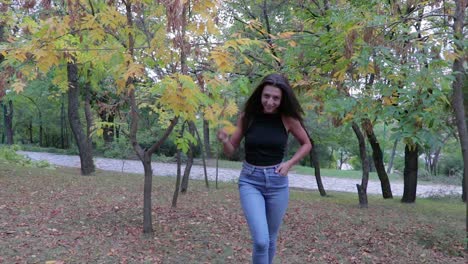 niña en un parque caminando y jugando con hojas de otoño