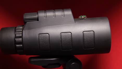 primer plano del teléfono móvil gigante lente de zoom óptico telescopio monocular en fondo rojo
