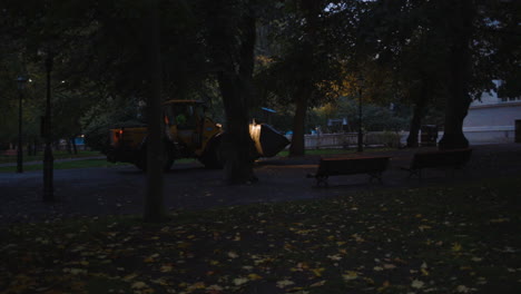 bulldozer drives through a park in the early morning during blue hour