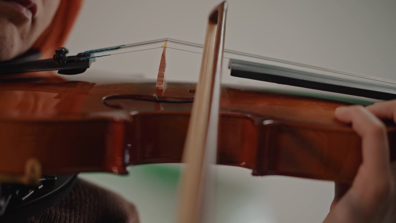 Delicate instrumentalist carefully crafting melodies with gentle movements and techniques. Artist meticulously producing refined musical tones through precise and tender bowing techniques