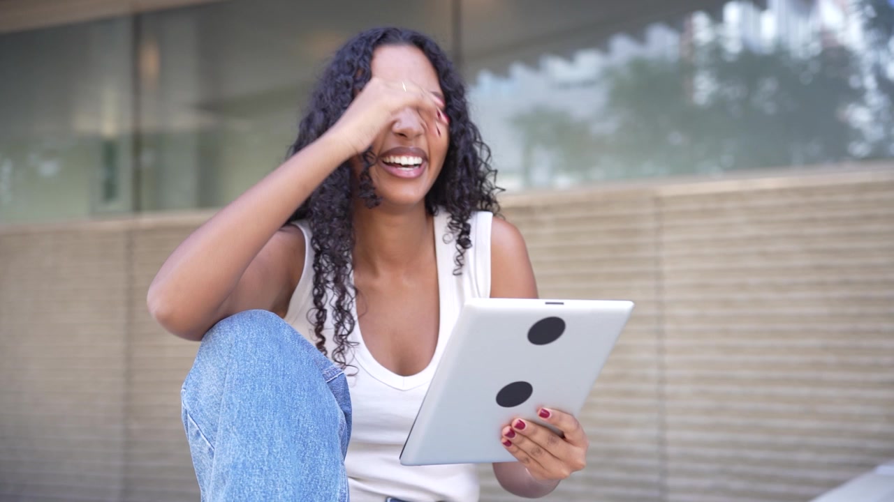 Una giovane donna intenta con il suo tablet all'aperto, mostrando uno sguardo di sorpresa e curiosità