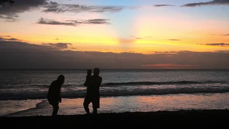 silhouetted family on beach at sunset