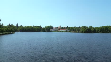 Long-narrow-wooden-jetty-Smooth-aerial-top-view-flight-Vacation-paradise-village-Chlum-at-Lake-Hejtman-in-Czech-Summer-day-2023