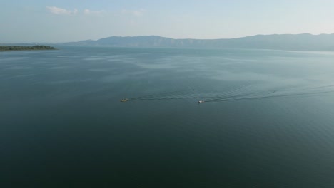 Aerial view of two boats on a calm lake with mountains in the background