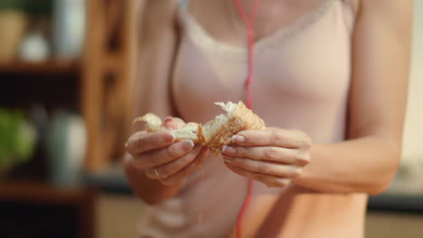 woman hands dunking croissant into coffee. brunette enjoying breakfast time.