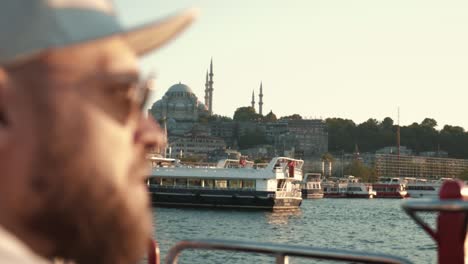 una toma cinematográfica de un feliz joven turista barbudo viendo una increíble puesta de sol de verano, vista de hagia sophia en un crucero.
