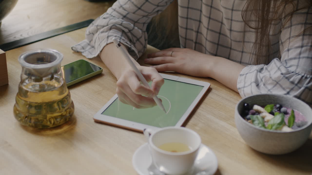 Woman working on a digital tablet in a cafe
