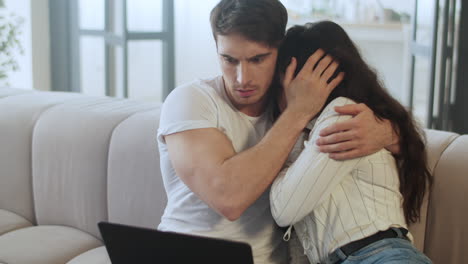 una pareja asustada viendo una computadora portátil en casa.