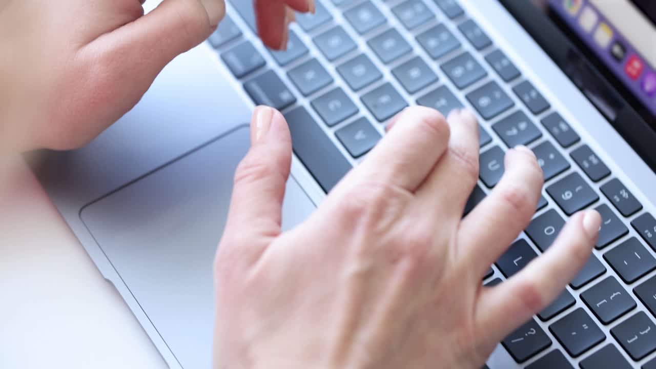 Female young hands are typing on laptop keyboard closeup