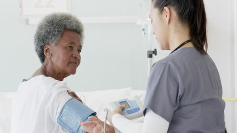 diversa doctora midiendo la presión arterial de una paciente de edad avanzada en una habitación de hospital, en cámara lenta