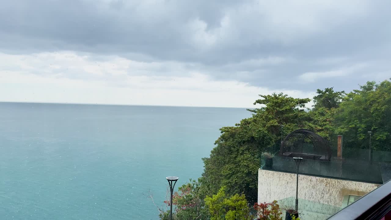 A serene view of the ocean from a restaurant in Phuket, Thailand, capturing the calm before a storm with overcast skies