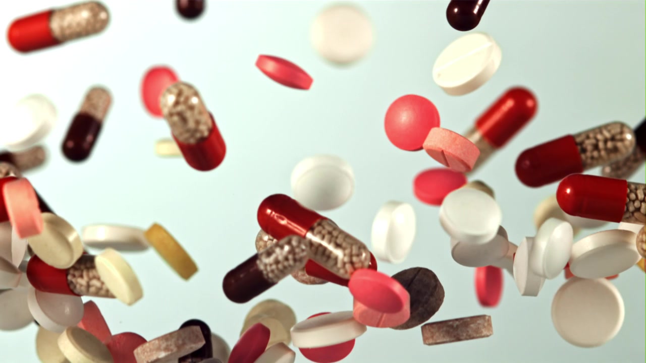 Colorful Medication Pills and Capsules Falling in Slow Motion