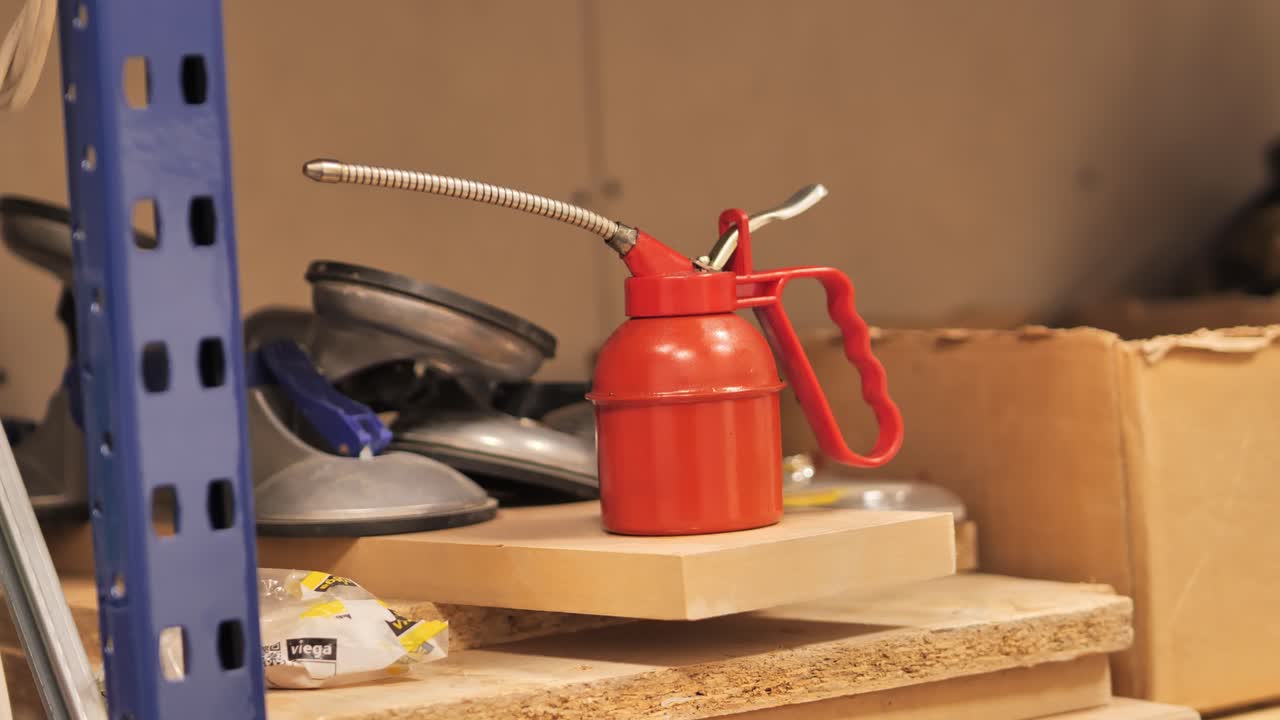 Static shot of red metal oil can tool used for mechanical maintenance work