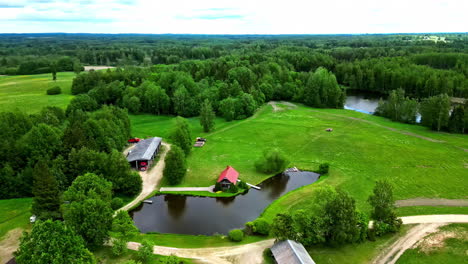 green landscape and small homestead on lake of small pond, aerial view