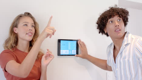adjusting smart home control panel, diverse couple showing curiosity and interest together