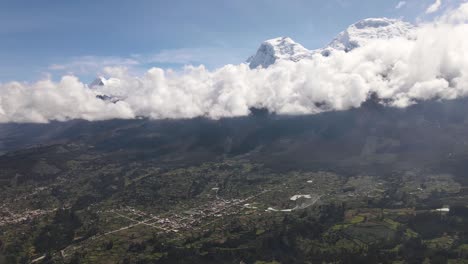 toma panorámica con drones del pico nevado de huascarán con nubes junto a un valle verde en la ciudad de yungay en perú