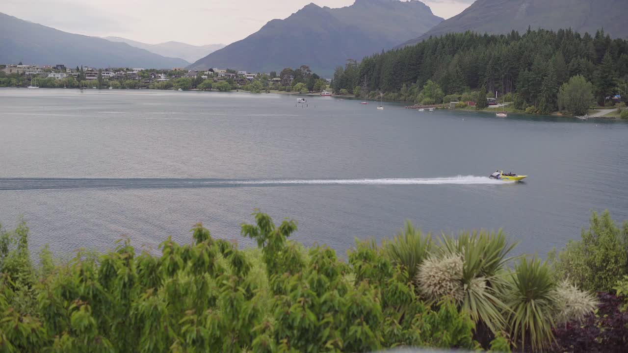 jet boat driving fast on the lake from left to right wide shot in queenstown