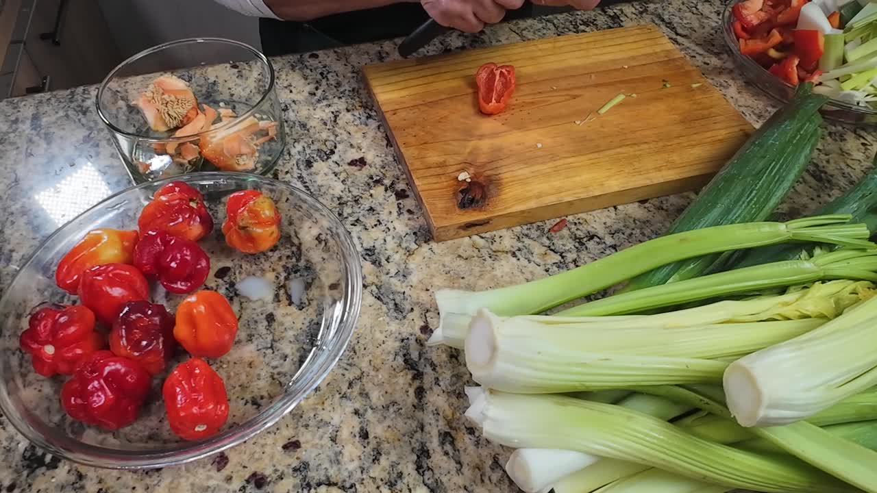 Donna anziana che taglia peperoni venezuelani freschi in una cucina accogliente