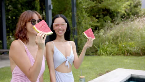 two female friends are enjoying slices of watermelon outdoors in the backyard