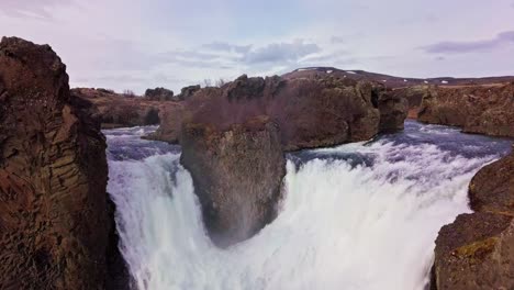 flyover twin waterfalls flowing around rocky terrain in iceland