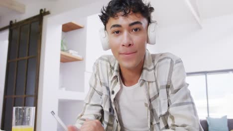 portrait of happy biracial male teenage boy having video call at home, slow motion