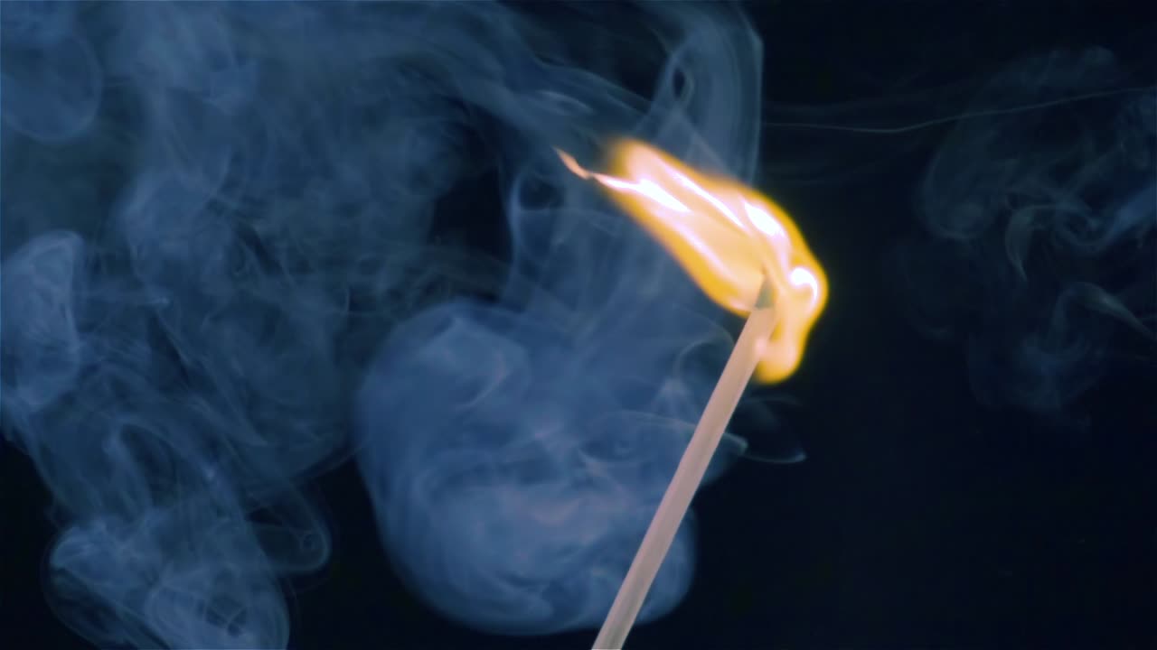 un fósforo ardiendo sobre un fondo negro en cámara lenta