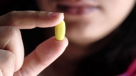 woman holding a yellow pill