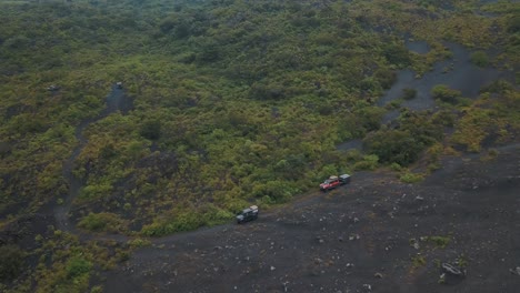 drone aerial view of cars driving off-road during camping trip to pacaya volcano in guatemala, central america