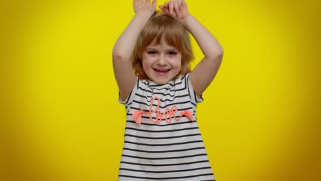 Lovely-funny-teen-kid-child-girl-smiling-friendly-and-doing-bunny-ears-gesture-on-head,-having-fun