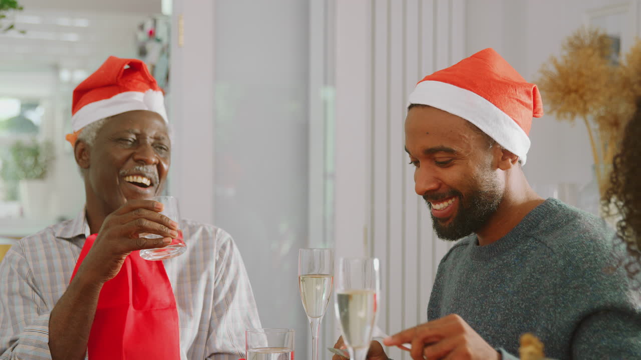 familia de varias generaciones con sombreros de santa disfrutando de la comida de navidad en casa juntos
