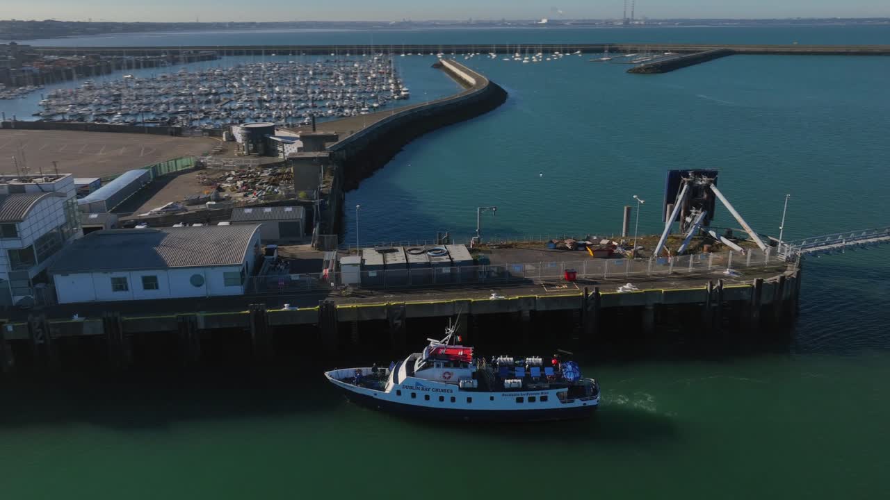 Dublin Bay Cruises Boat, Dún Laoghaire, County Dublin, Ireland, September 2024. Drone orbits counter clockwise keeping the tour boat in frame as it approaches the old Ferry Terminal Pier.