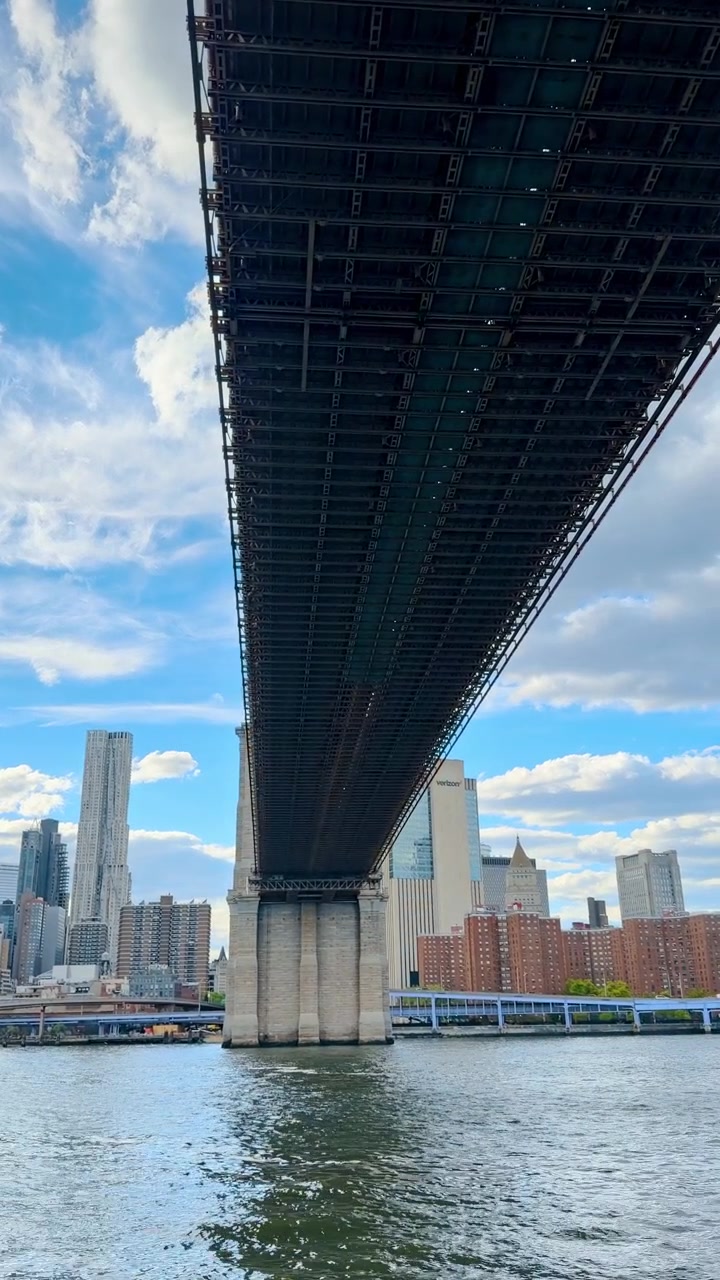 New York, USA, 1 maggio 2026: Vista dal basso della struttura in acciaio del Ponte di Brooklyn sull'East River. Scatto in prospettiva dal basso che guarda la parte inferiore del Ponte di Brooklyn con lo skyline di New York City