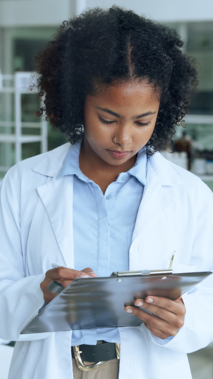 Young Woman in Lab Coat Writing on Clipboard in Laboratory