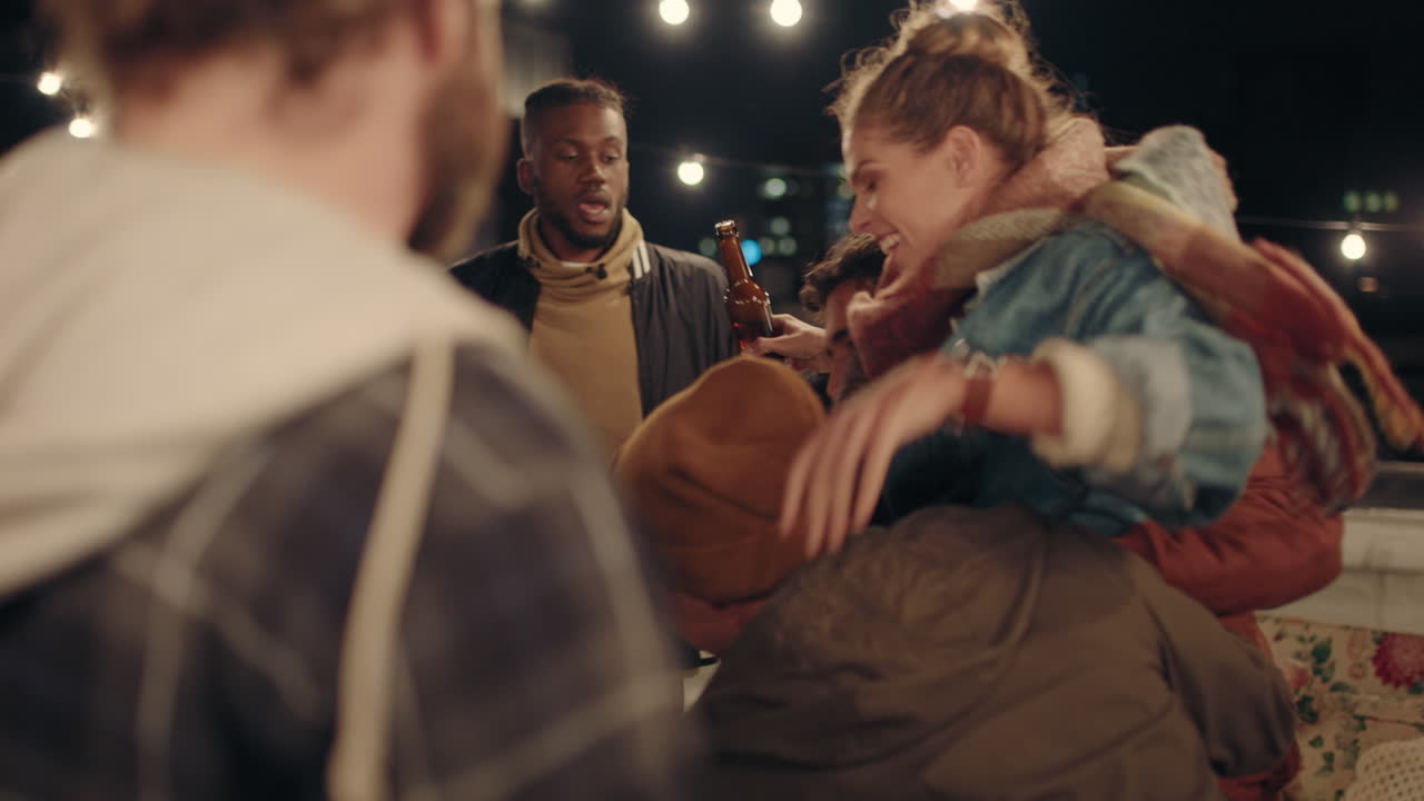 young group of multiracial friends having fun dancing playfully together enjoying rooftop party at night laughing celebrating friendship
